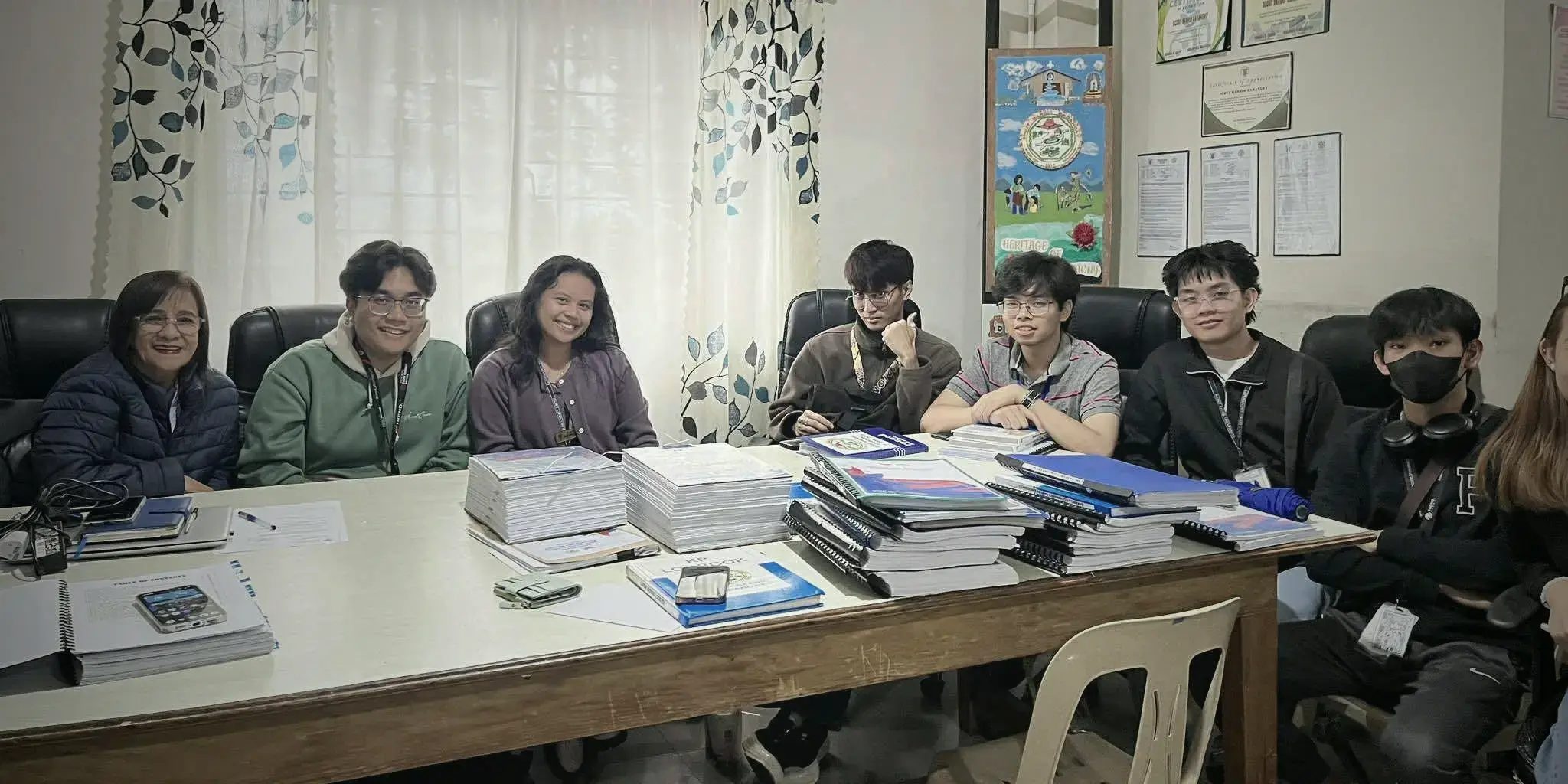 The intern group with their supervisor at the office table, document stacks between them
